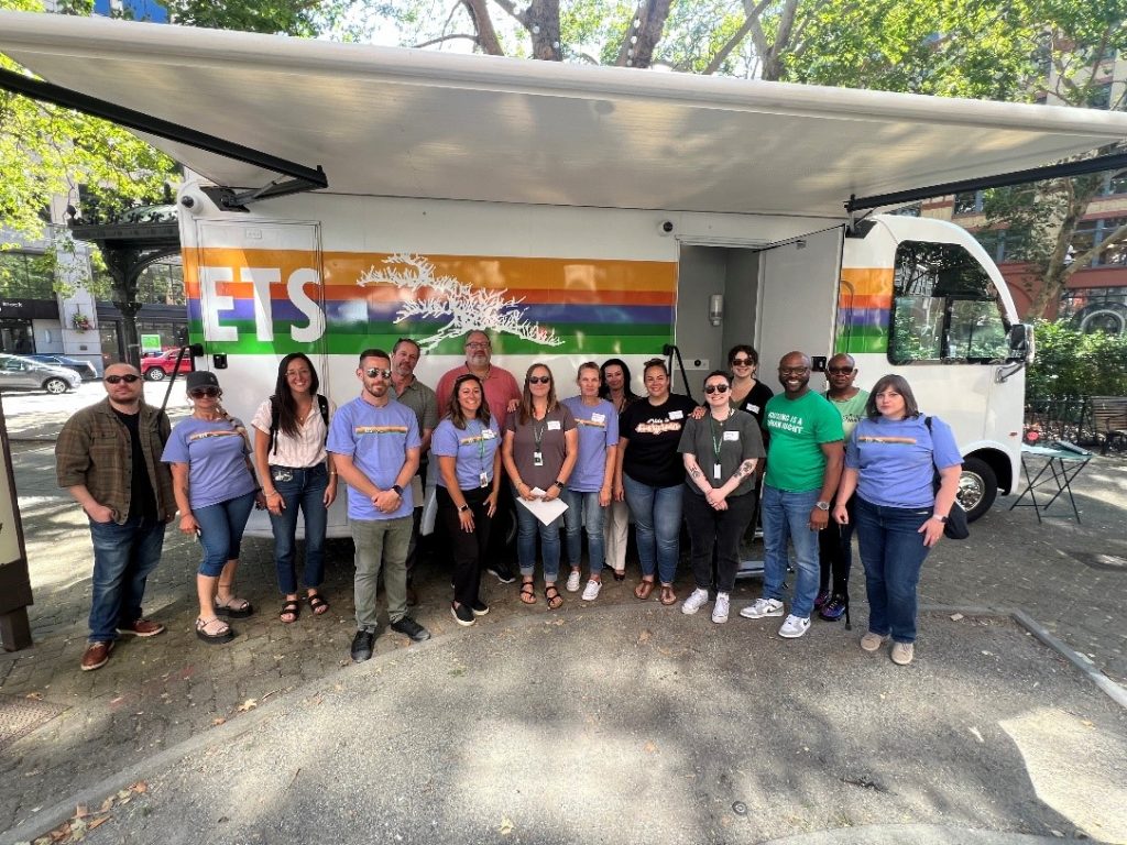 A crowd of ETS team members stands in front of the new Treatment in Motion vehicle.