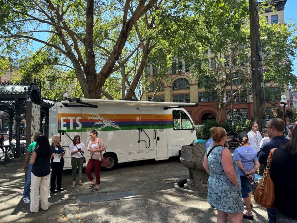 People mingle in front of the vehicle parked in Pioneer Square.