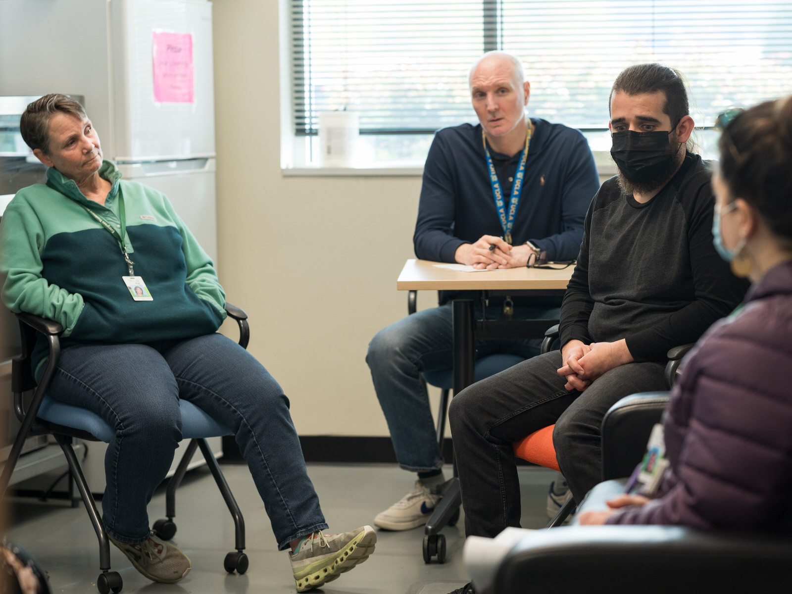 Several people sit at desks in a group talking.